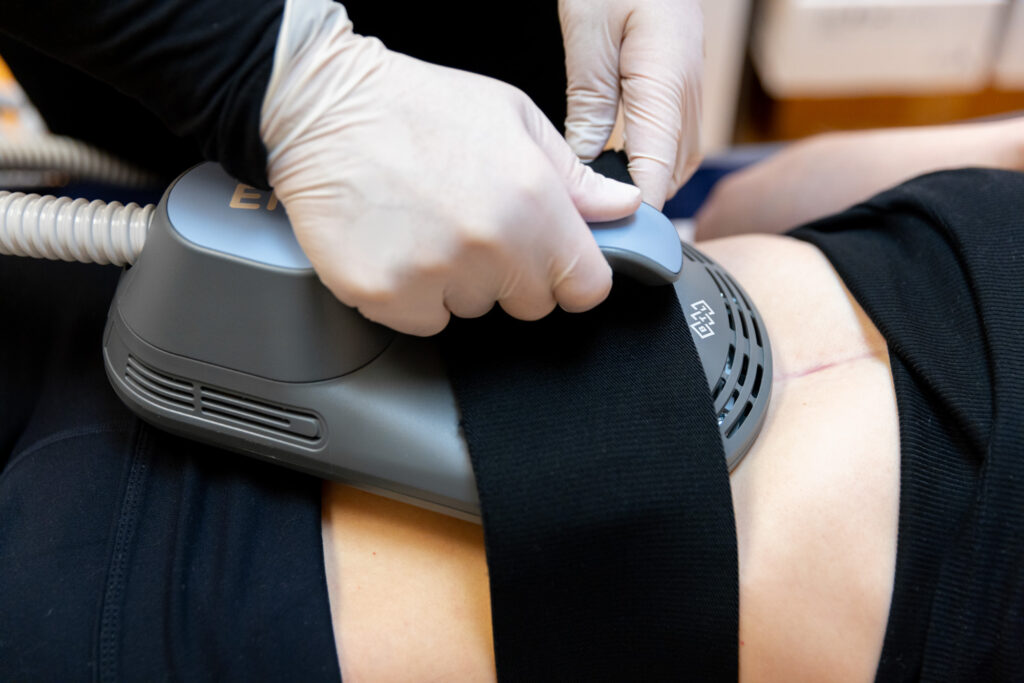 One of our team members straps an abdominal applicator to a patient's torso to prep for a session of Emsculpt NEO near Barrington Hills.