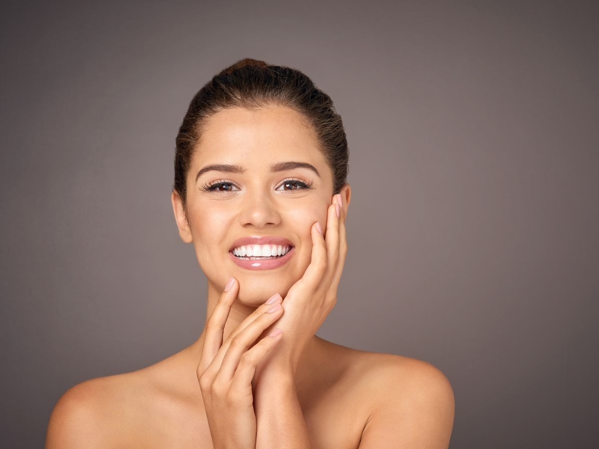 A woman smiles as she examines the results of laser hair removal near Elgin, IL.