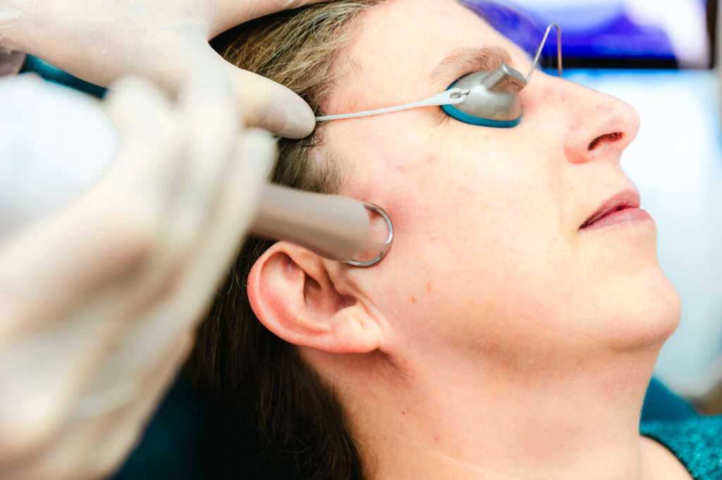 A patient with protective eyewear relaxes as a specialist applies the UltraClear laser for her nonsurgical facelift in Elgin at our office.